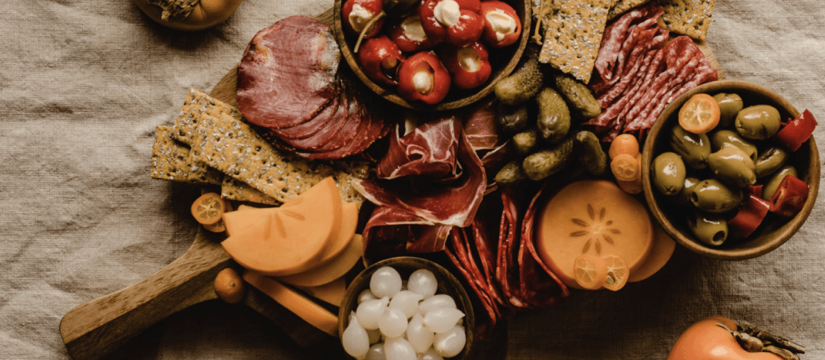 A set of marinated olives, pickles and sausages.