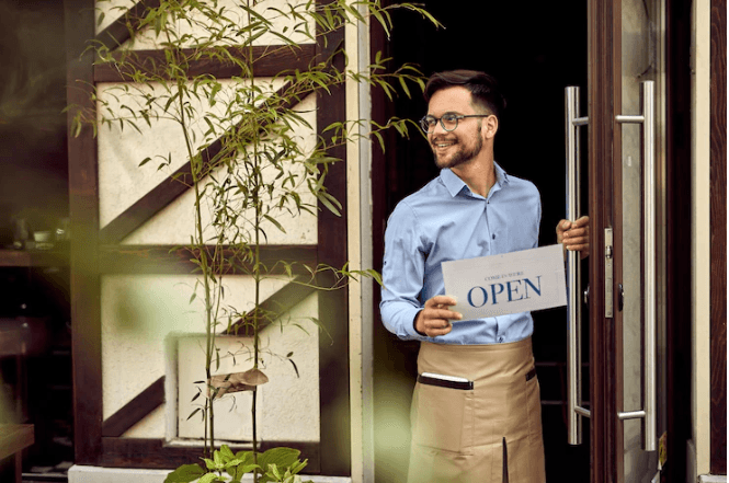 A waiter is putting the open sign to the restaurant door.