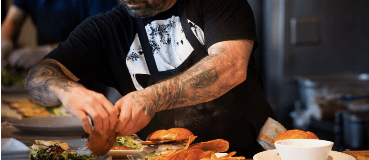 A cook is working on burgers.