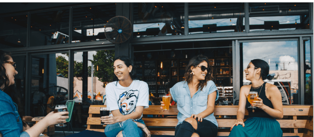 Four young ladies drink beer and laugh.