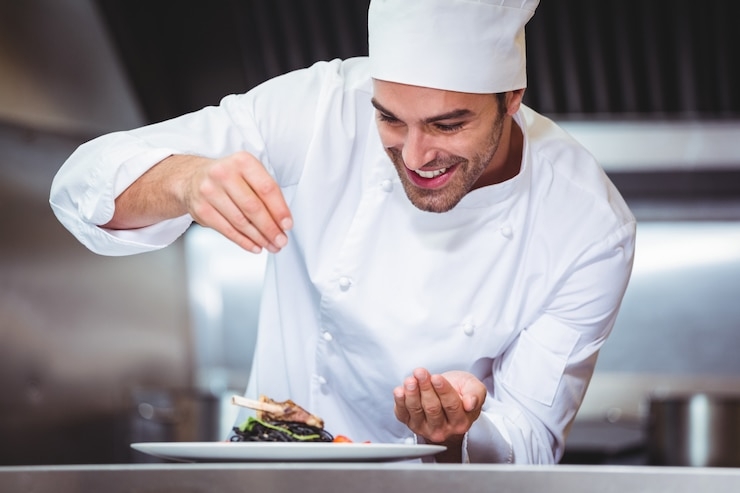 A cook is adding final additions to a dish.