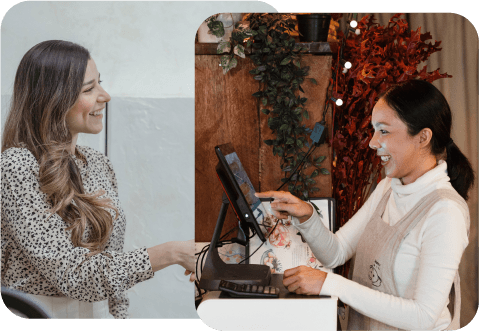 A cashier serves to a customer smiling at each other.