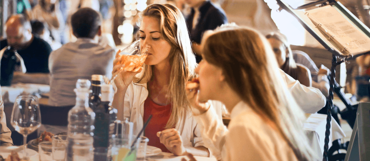 Two young girls are having a lunch in the restaurant.