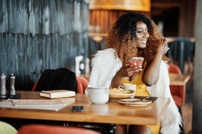 A woman is having lunch in the restaurant and stares somewhere at a phone in her hand.