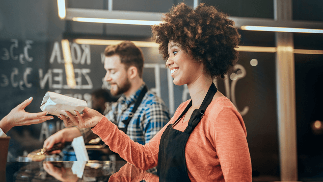 A curly-haired waiter gives an order to a customer.