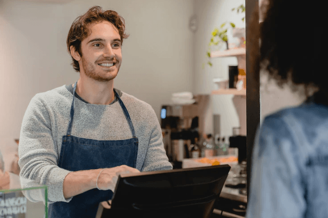 A cashier smiles at the customer.