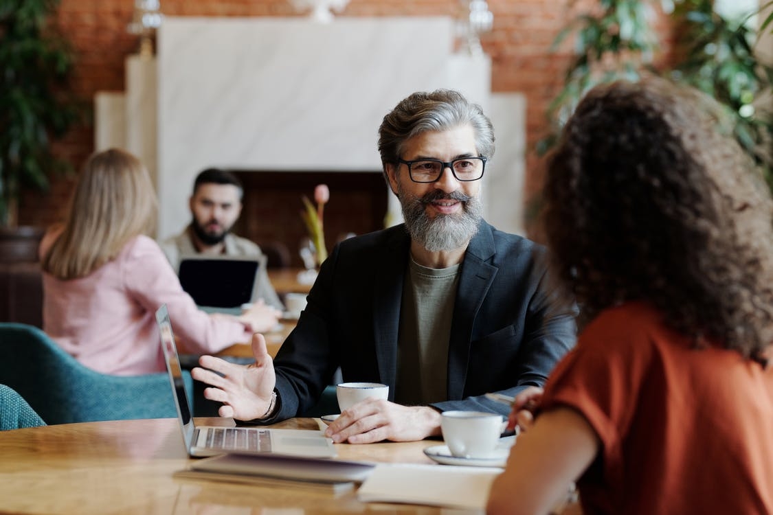 A man with beard is talking with a girl in the restaurant.