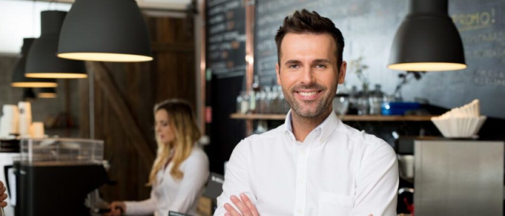 A waiter smiles to camera and poses for a picture.