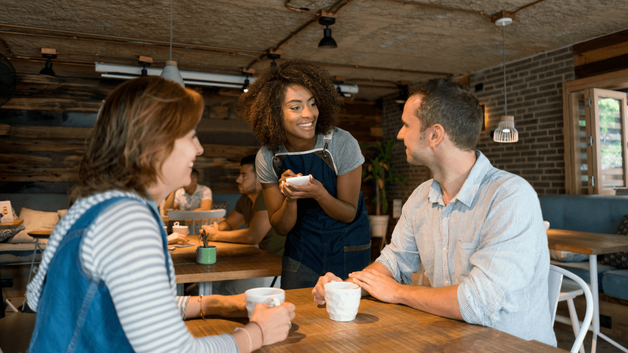 A waiter is taking an order from the couple in the restaurant.