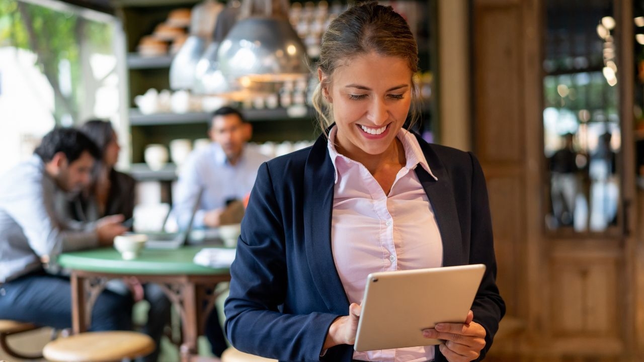 A restaurant manager looks at her tablet smilingly.