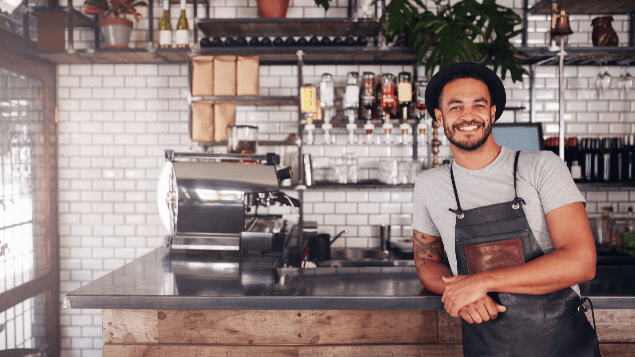 A waiter poses for a phone and smiles.