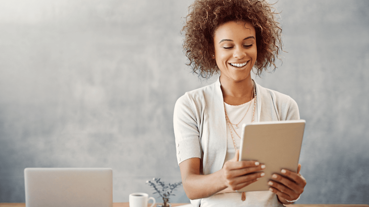 A young girl stares to her laptop smilingly.